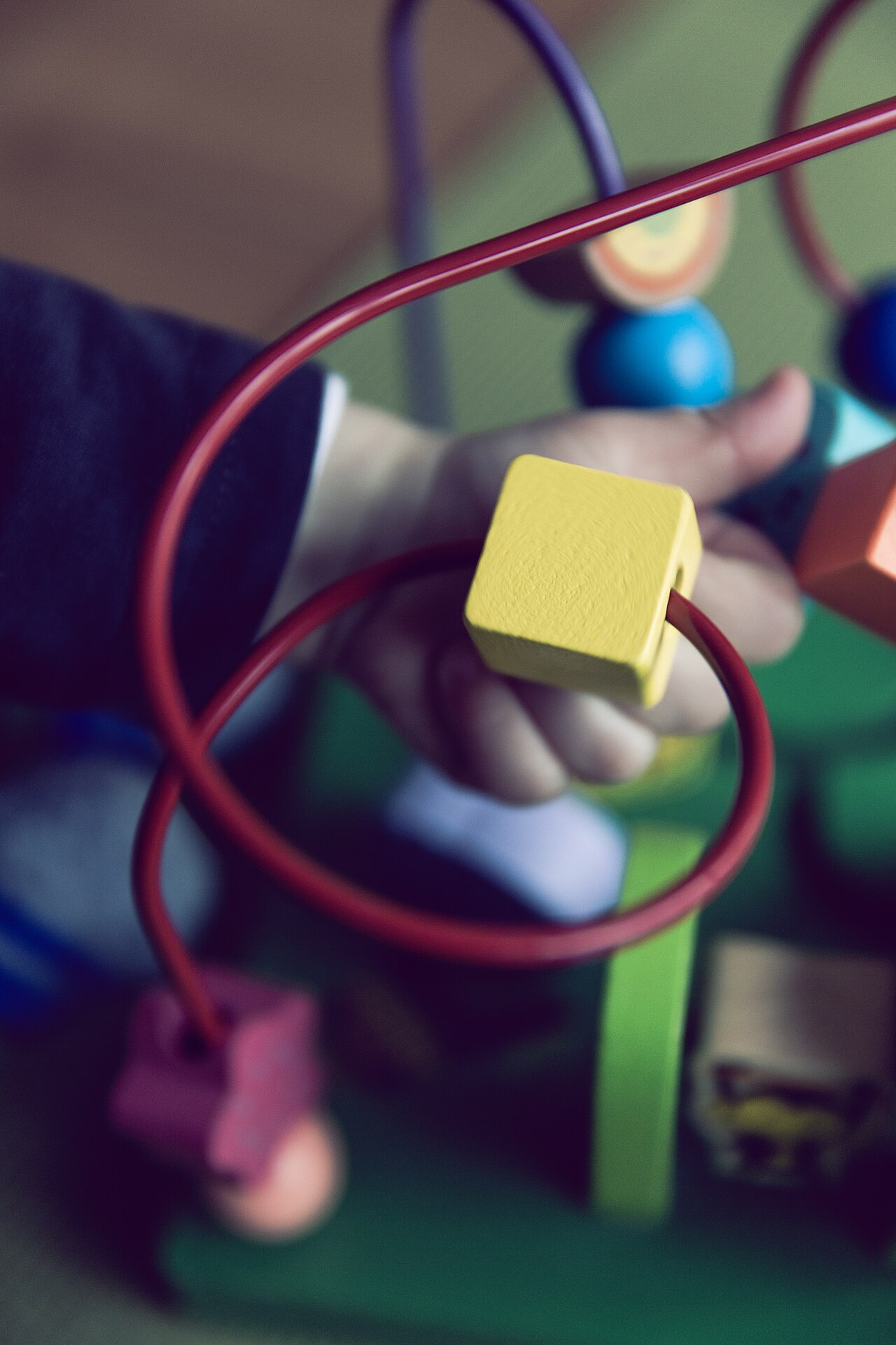 A child’s hand playing with a wooden bead maze toy
